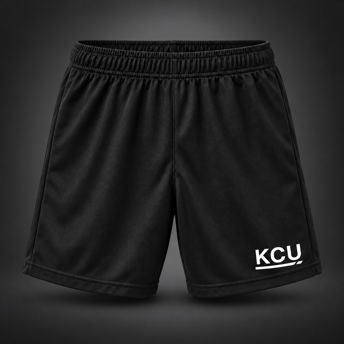 Black youth athletic shorts with a white KCU monogram near the left front hem.
